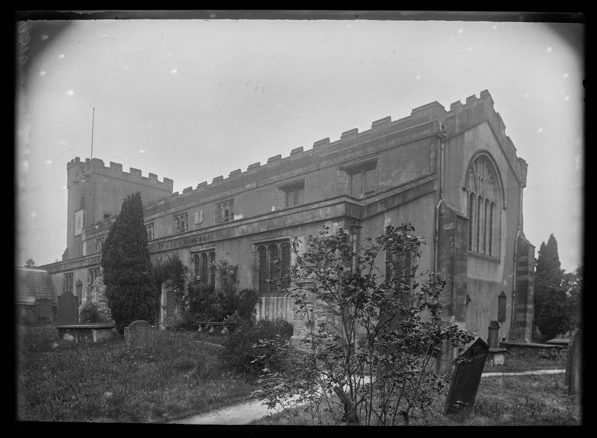A black and white photograph of a Crosthwaite, saint Kentigern's church with tombstones in the foreground.