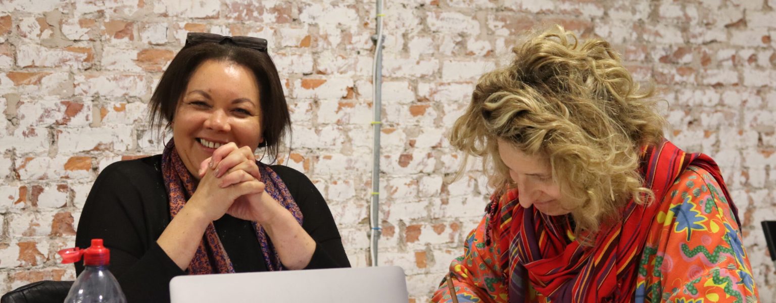 Previous creative workshop. Two participants are smiling and one is writing