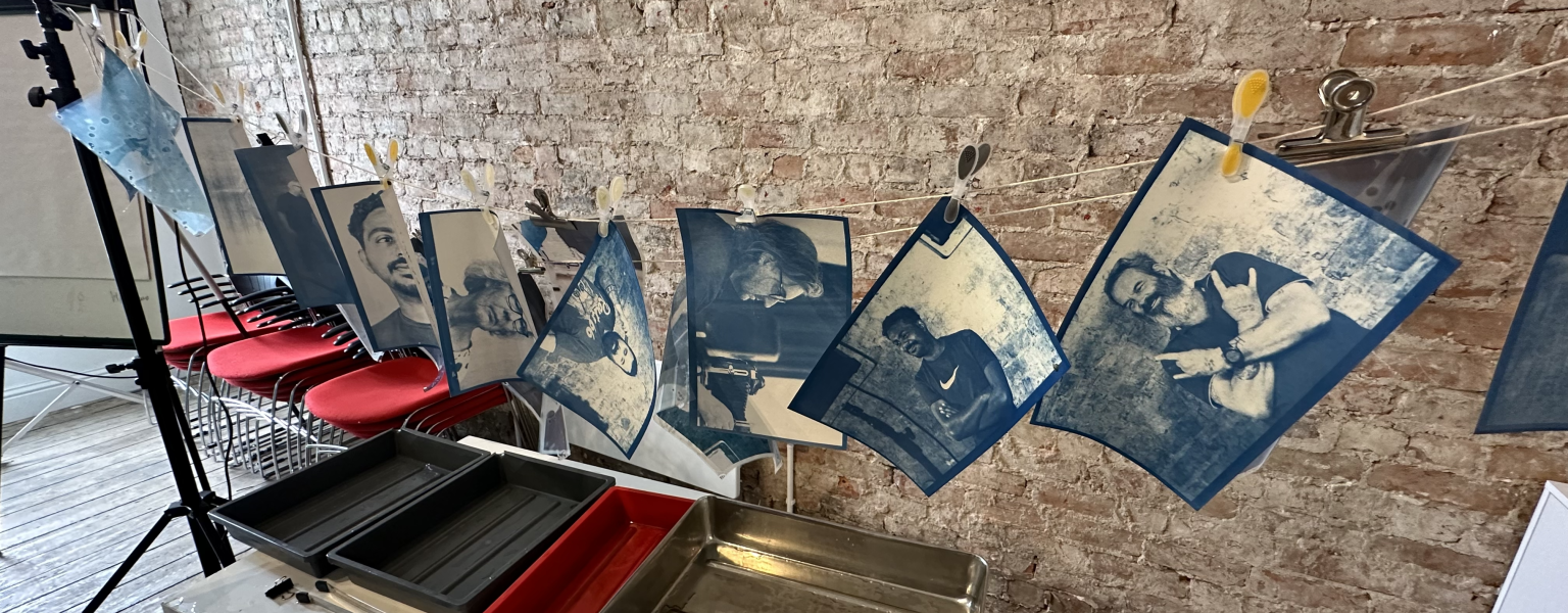 Image shows a collection of hanging Cyanotype prints from a previous photography workshop with Philip Green