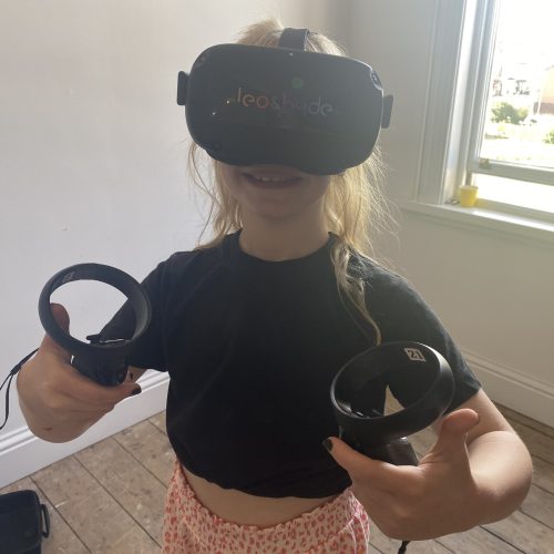 The image shows a young child from one of our previous family days, enjoying playing with a virtual reality headset.